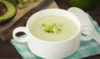 Refreshing avocado soup with yogurt, garnished with fresh herbs and a drizzle of olive oil