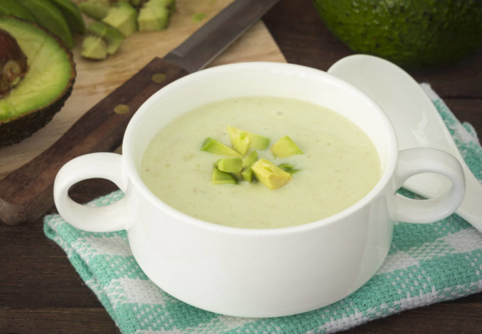 Refreshing avocado soup with yogurt, garnished with fresh herbs and a drizzle of olive oil